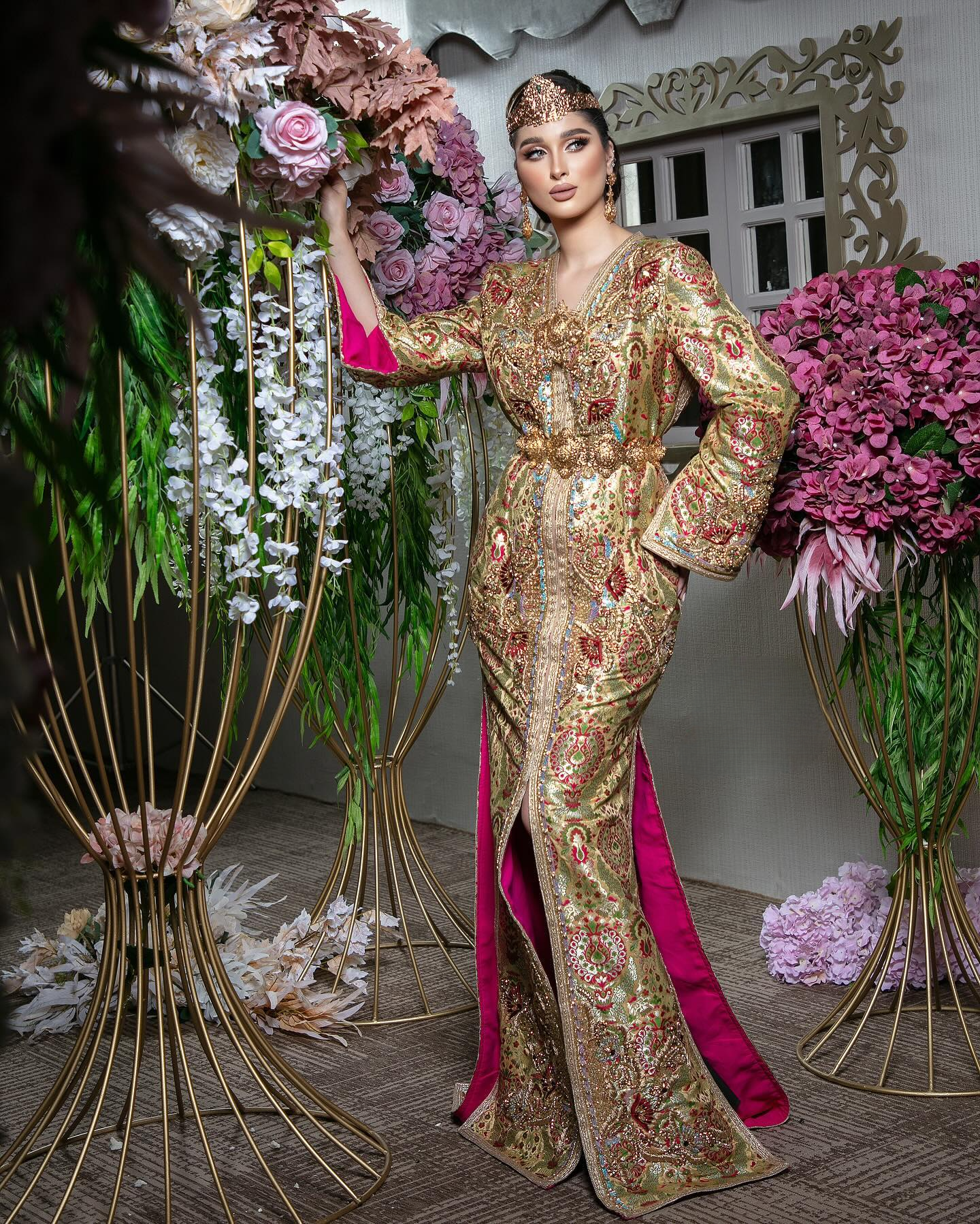 a woman in a gold caftan dress holding flowers